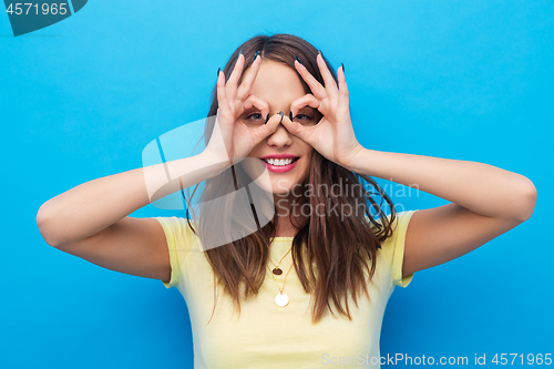 Image of young woman looking through finger glasses