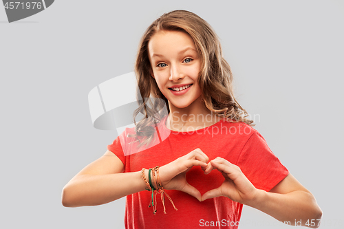 Image of smiling teenage girl in red making hand heart