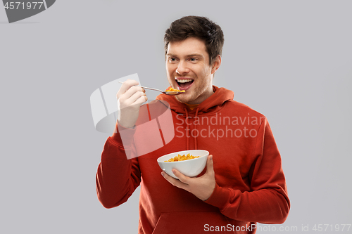 Image of smiling young man in red hoodie eating cereals