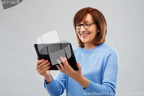 Image of senior woman in glasses using tablet computer