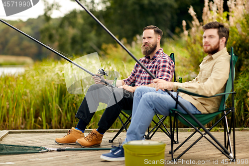 Image of friends with fishing rods at lake or river