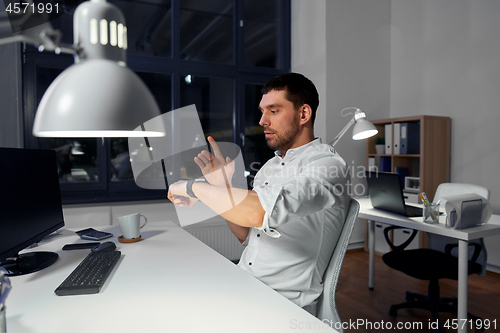 Image of businessman using smart watch at nigh office