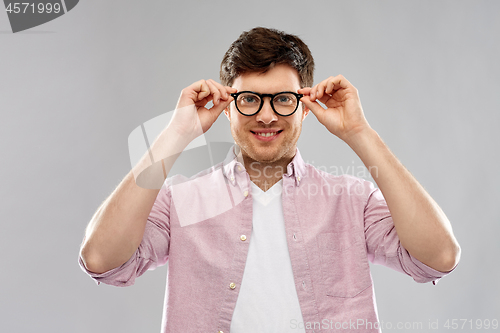 Image of smiling young man in glasses over grey background