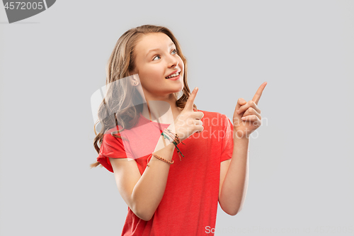 Image of smiling teenage girl pointing fingers to something