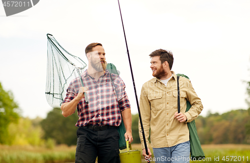 Image of friends with fishing rods and net at lake or river