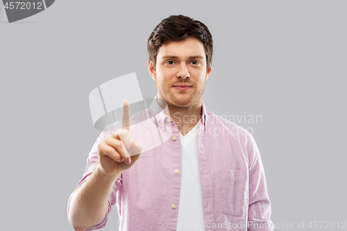 Image of young man showing one finger over grey background