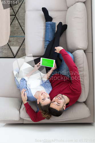 Image of couple relaxing at  home with tablet computers