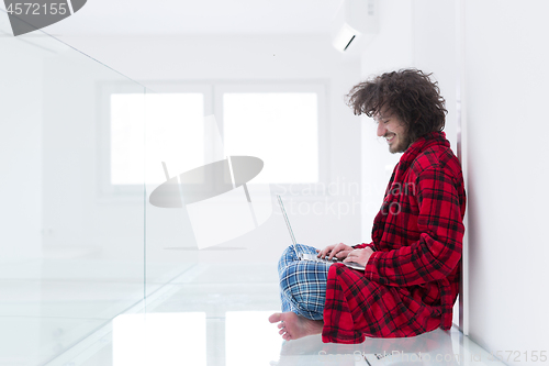 Image of young freelancer in bathrobe working from home