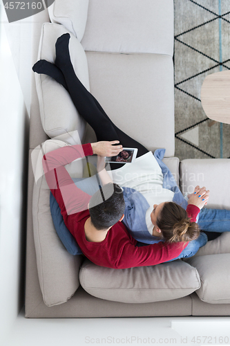 Image of couple relaxing at  home with tablet computers