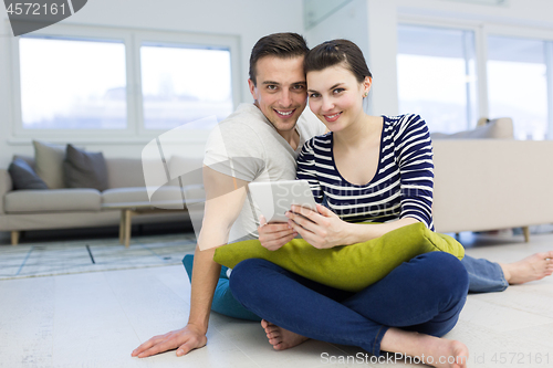 Image of Young Couple using digital tablet on the floor