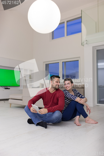 Image of Young Couple using digital tablet on the floor