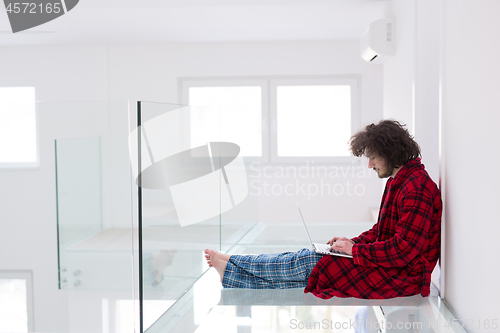 Image of young freelancer in bathrobe working from home