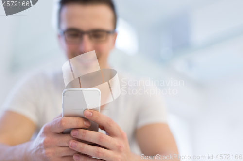 Image of young man using a mobile phone  at home