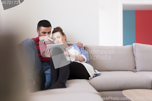 Image of couple relaxing at  home with tablet computers