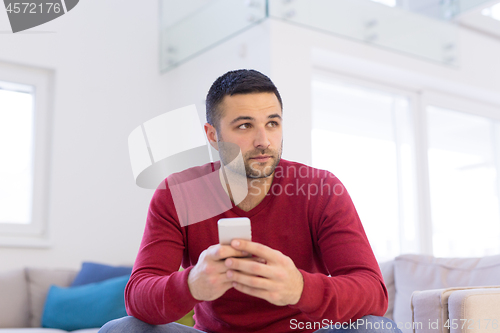 Image of young man using a mobile phone  at home