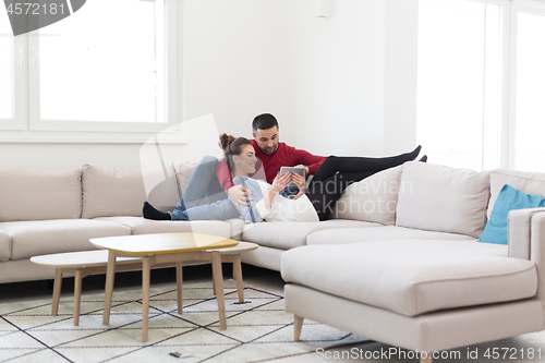 Image of couple relaxing at  home with tablet computers