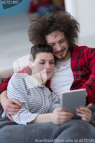 Image of couple relaxing at  home with tablet computers