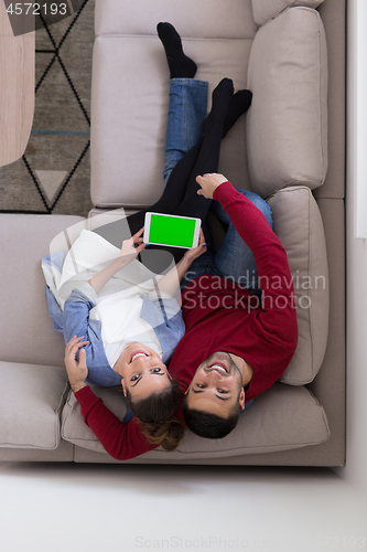 Image of couple relaxing at  home with tablet computers