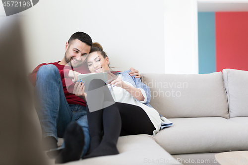 Image of couple relaxing at  home with tablet computers