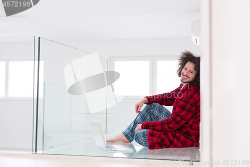 Image of young freelancer in bathrobe working from home