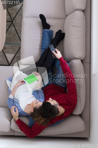 Image of Young couple on the sofa watching television top view