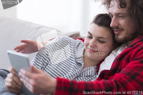 Image of couple relaxing at  home with tablet computers