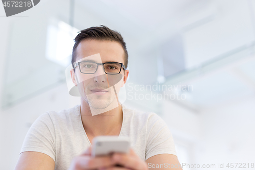 Image of young man using a mobile phone  at home