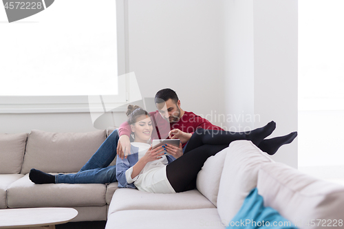 Image of couple relaxing at  home with tablet computers