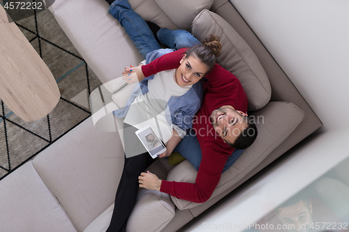 Image of couple relaxing at  home with tablet computers