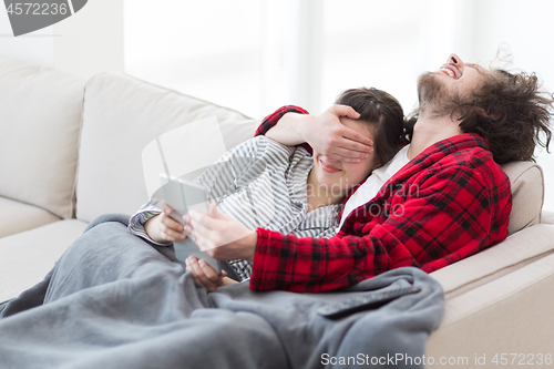 Image of couple relaxing at  home with tablet computers