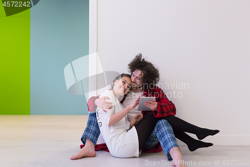 Image of Young Couple using digital tablet on the floor