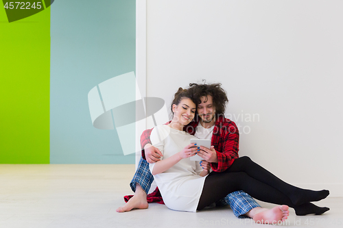 Image of Young Couple using digital tablet on the floor