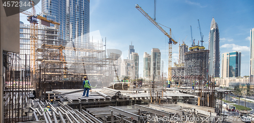 Image of Laborers working on modern constraction site works in Dubai. Fast urban development consept