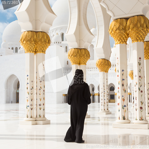 Image of Traditionally dressed arabic woman wearing black burka wisiting Sheikh Zayed Grand Mosque in Abu Dhabi, United Arab Emirates