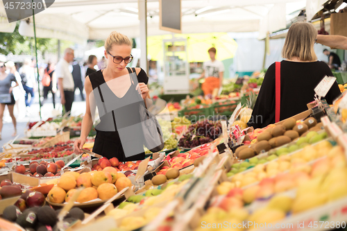 Image of Woman buying fruits and vegetables at local food market. Market stall with variety of organic vegetable