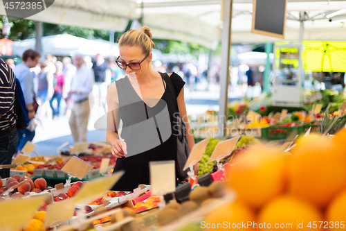 Image of Woman buying fruits and vegetables at local food market. Market stall with variety of organic vegetable