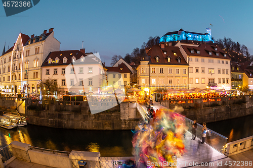 Image of View of lively river Ljubljanica bank in old city center decorated with Christmas lights at dusk. Old medieval Ljubljana cstle on the hill obove the city. Ljubljana, Slovenia, Europe