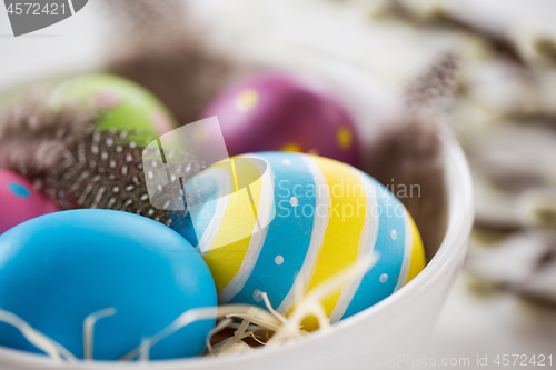 Image of close up of colored eggs and feathers in bowl