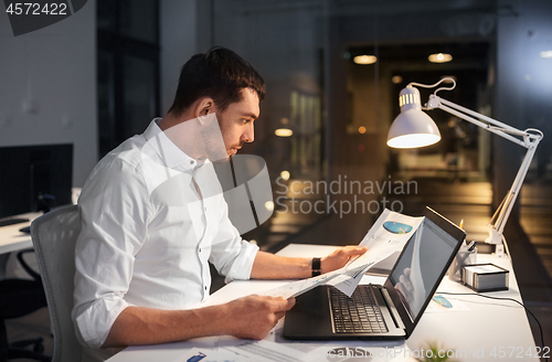 Image of businessman with laptop working at night office