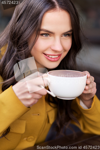 Image of teenage girl drinking hot chocolate at city cafe