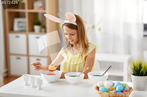 Image of girl coloring easter eggs by liquid dye at home