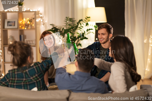 Image of friends clinking drinks at home in evening