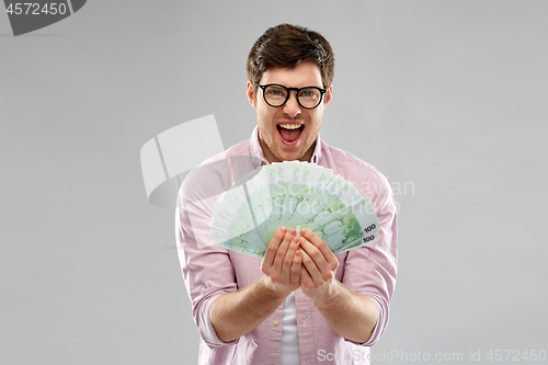 Image of happy young man in glasses with fan of euro money