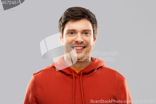 Image of smiling young man in red hoodie over grey