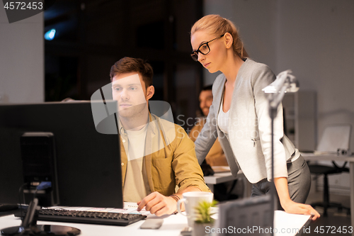 Image of business team with computer working late at office