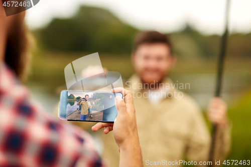 Image of friend photographing fisherman by smartphone