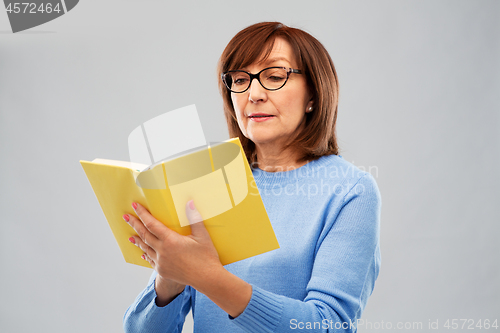 Image of senior woman in glasses reading book