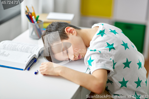 Image of tired student boy sleeping on table at home