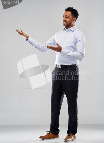 Image of indian businessman holding something over grey