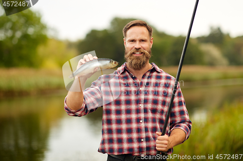 Image of bearded fisherman with fishing rod and fish catch